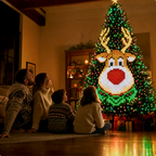 Family sitting on the floor looking up at a Christmas tree lit with a reindeer pattern